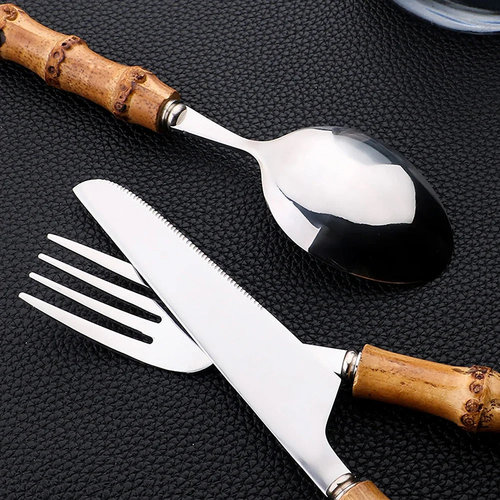 Set di posate da 16 pezzi in acciaio inossidabile con manico in bambù naturale, include forchette, cucchiai, coltelli e stoviglie.
